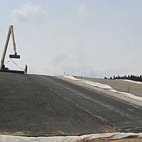 Workers apply a sand protection layer over the already laid GTD to provide additional protection and stability