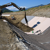 Abdeckung des Gewässerkanals durch den Einbau von Betonmatten und anschließender Sandfüllung mithilfe eines Baggers