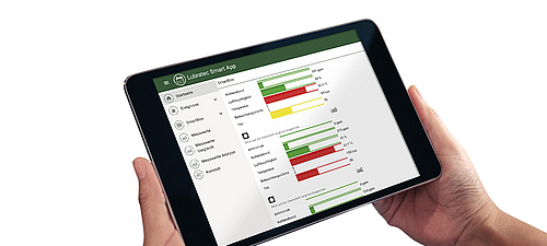 Übersichtliches Stallklima-Dashboard in der Lubratec SmartApp Person hält Tablet mit gestarteter Lubratec SmartApp, auf der ein übersichtliches Dashboard für das Stallklima zu sehen ist