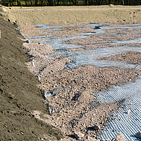 Basetrac Grid Geogitter auf einer Baustelle, über das teilweise schon Sand oder Kies verteilt wurde