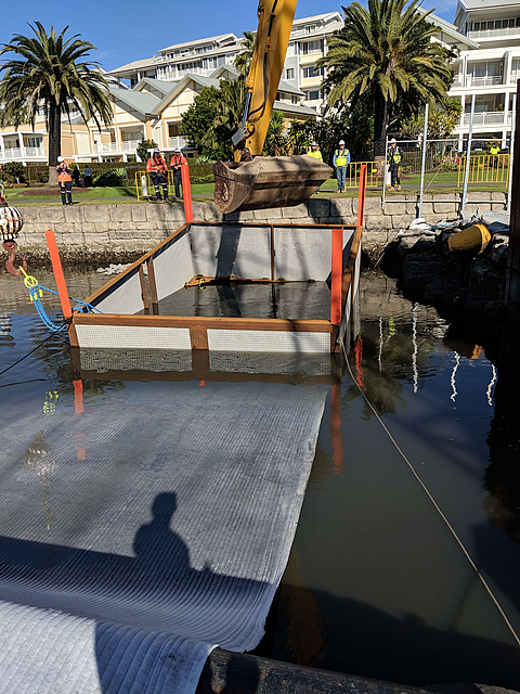 Aktivkohle Geokomposit wird ins Wasser gelassen
