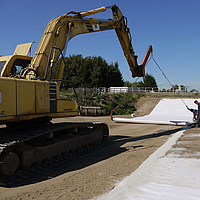 Bagger verwendet eine Verlegetraverse zum Ausrollen von Tektoseal® Clay Bentonitmatten