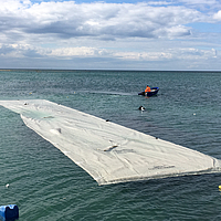 Vorkonfektioniereter und noch nicht befüllter Schlauch ausgebreitet auf dem Wasser und bereit zur Installation im Wasser