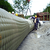 Arbeiter befüllen das Incomat® Pipeline Cover mit Betonpumpe über den Einfüllstutzen