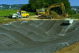 Nahaufnahme des Einbaus von Betonmatten zur Abdichtung und Erosionssicherung des Regenrückhaltebeckens 