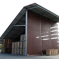 Windschutznetz an einer Lagerhalle für Holzspalten