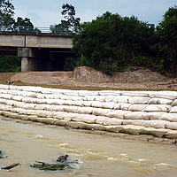Sandsäcke am Flussrand für Uferschutz