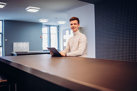 Auszubildender zum Industriekaufmann mit Laptop an der Kommunikationstheke im Bürogebäude am Standort Gescher