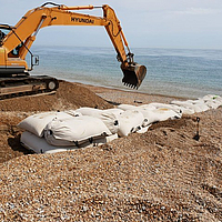 Einbau von SoilTain Bags an einem Kiesstrand mit Bagger für den Hochwasserschutz