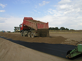 Erde wird auf Fortrac A Geogitter-Rollen gekippt, bestehend aus hochfestem Aramid, ideal für Erdfallüberbrückung