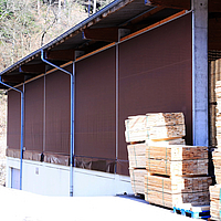 Braune Windschutznetze als Verkleindung einer Lagerhalle für Holz