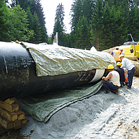 Arbeiter bringen das Incomat® Pipeline Cover am Rohrabschnitt an