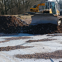 Planierraupe bei der Arbeit, verteilt Geröll auf einer Baustelle