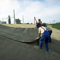 Arbeiter beim Prozess der Verlegung der HUESKER Bentonitmatte auf einer Baustelle zur Abdichtung
